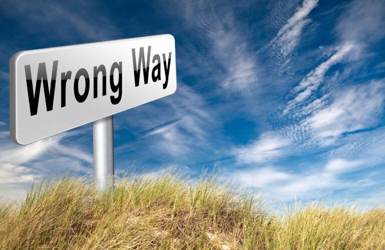 Ein „Wrong Way“-Schild steht inmitten von hohem Gras unter einem teilweise bewölkten Himmel und wirft eine Reflexion auf die Reise zum Selbstwertgefühl.